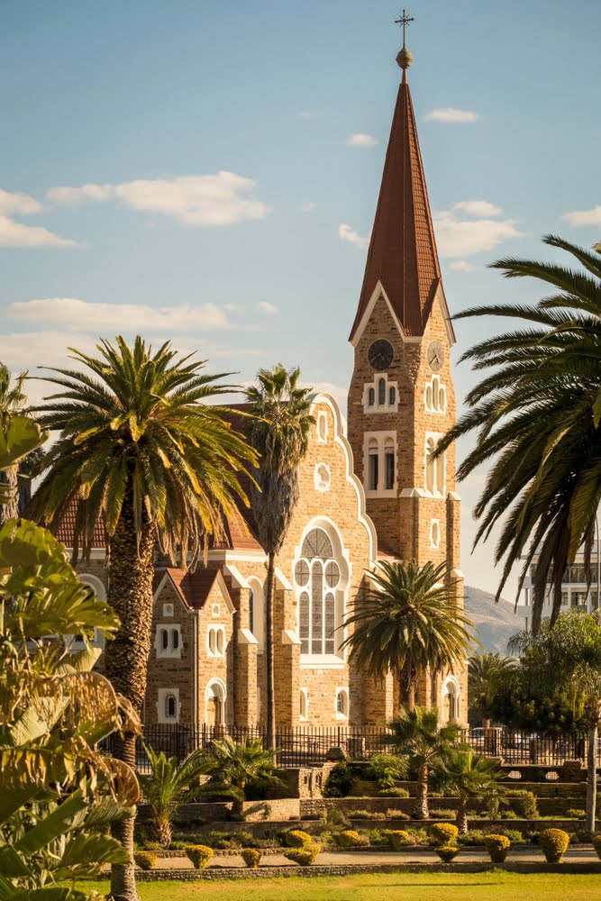 Die historische Christuskirche in Windhoek, Namibia, umgeben von Palmen und gepflegten Gartenanlagen im Stadtzentrum.